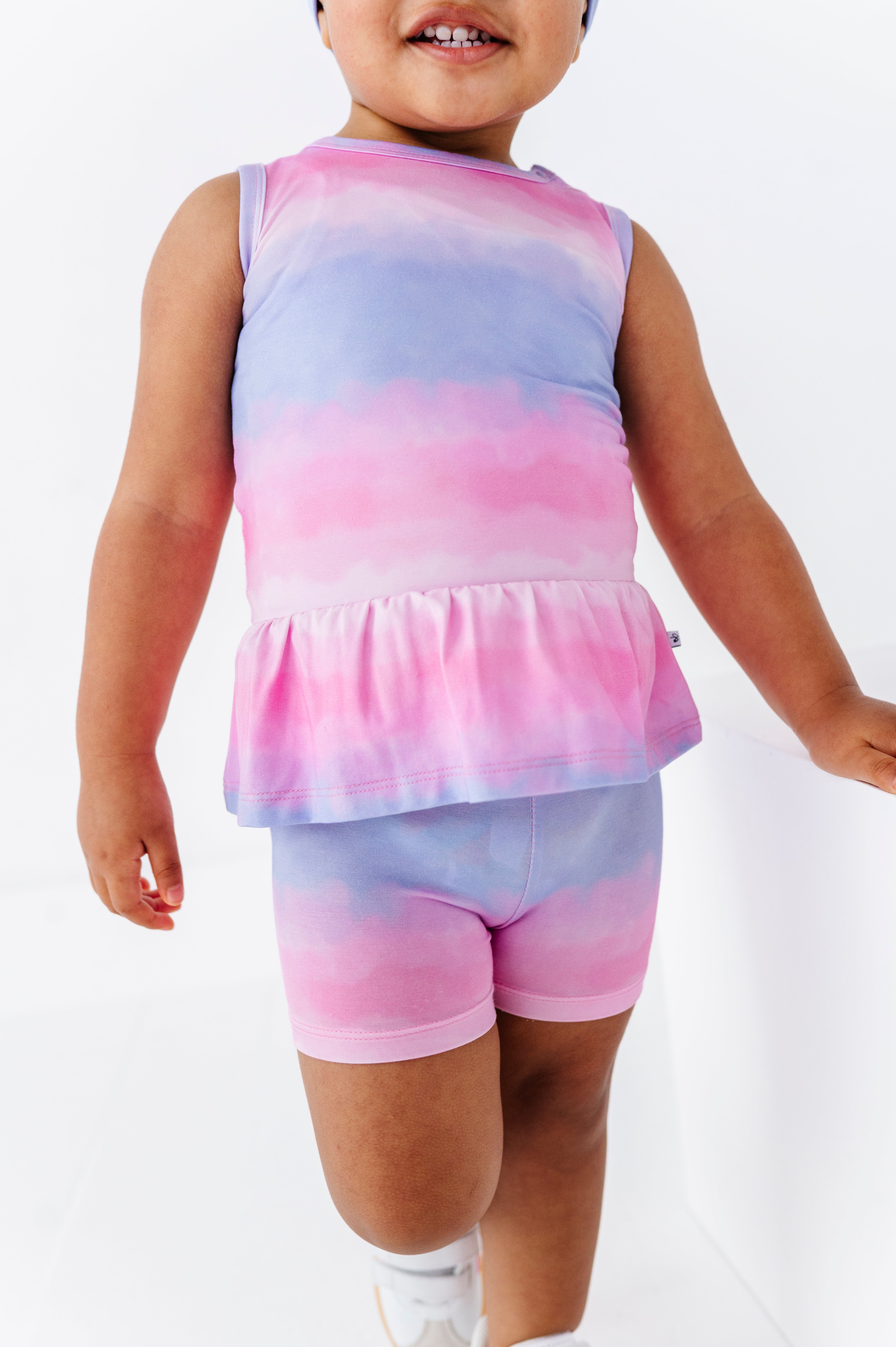 Child wearing a tie-dye sleeveless top and shorts set on a white background
